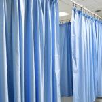 Blue hospital privacy curtains in a medical facility for patient separation and infection control.