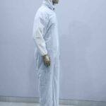 Side view of disposable white coverall suit with hood and boot covers for protective use in medical and industrial environments.
