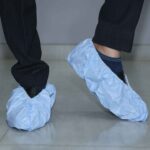 Disposable blue shoe covers worn over shoes for cleanroom or medical use