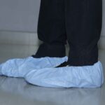 Disposable blue shoe covers worn over shoes for industrial or medical use